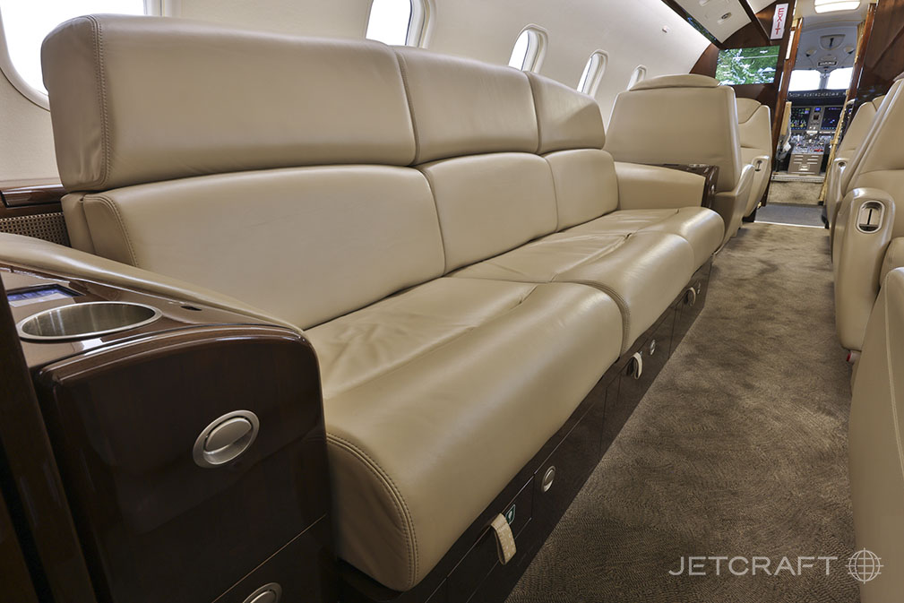 The interior of the Challenger aircraft features a leather sofa and wood trim.